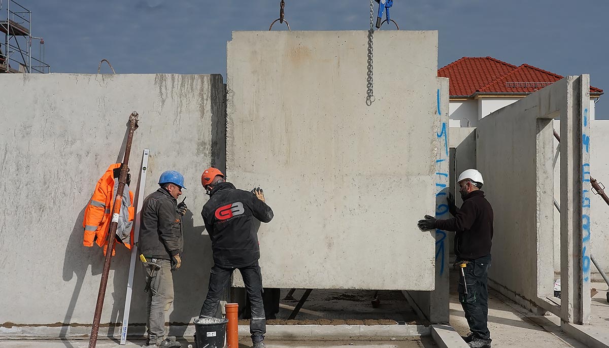 Das Team der Grotjahn Baugesellschaft fügt eine Betonfertigwand in den Rohbau ein.